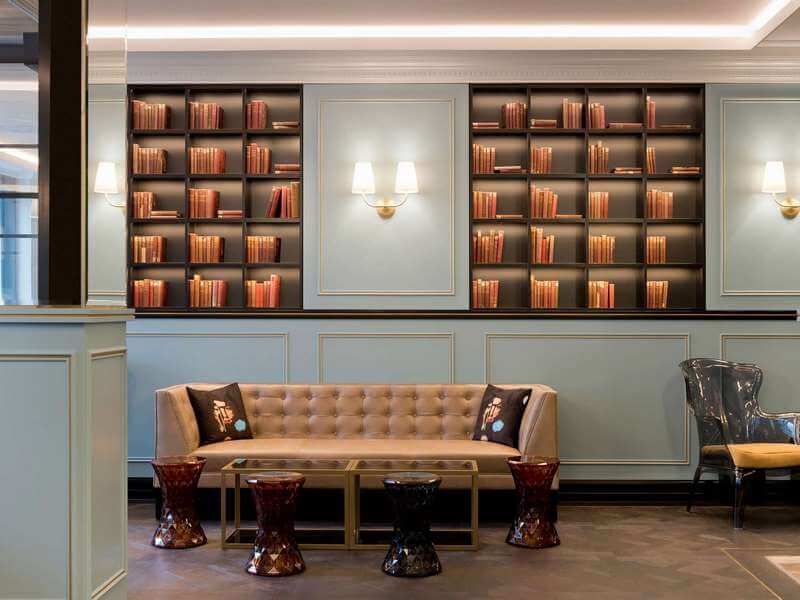 Un coin salon aménagé dans l'ambiance feutrée d'une bibliothèque (c) Hôtel Rotary MGallery-Genève
